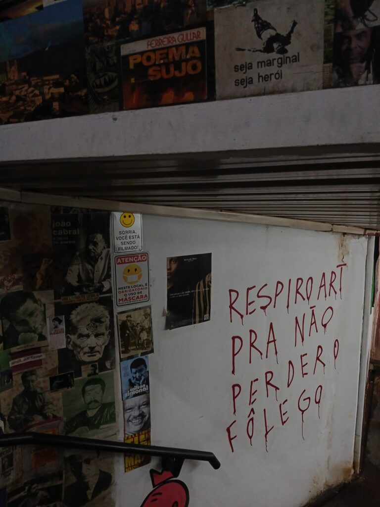 Foto de uma parede com vários pôsteres de artistas famosos, e com a frase "respiro art pra não perder o fôlego"